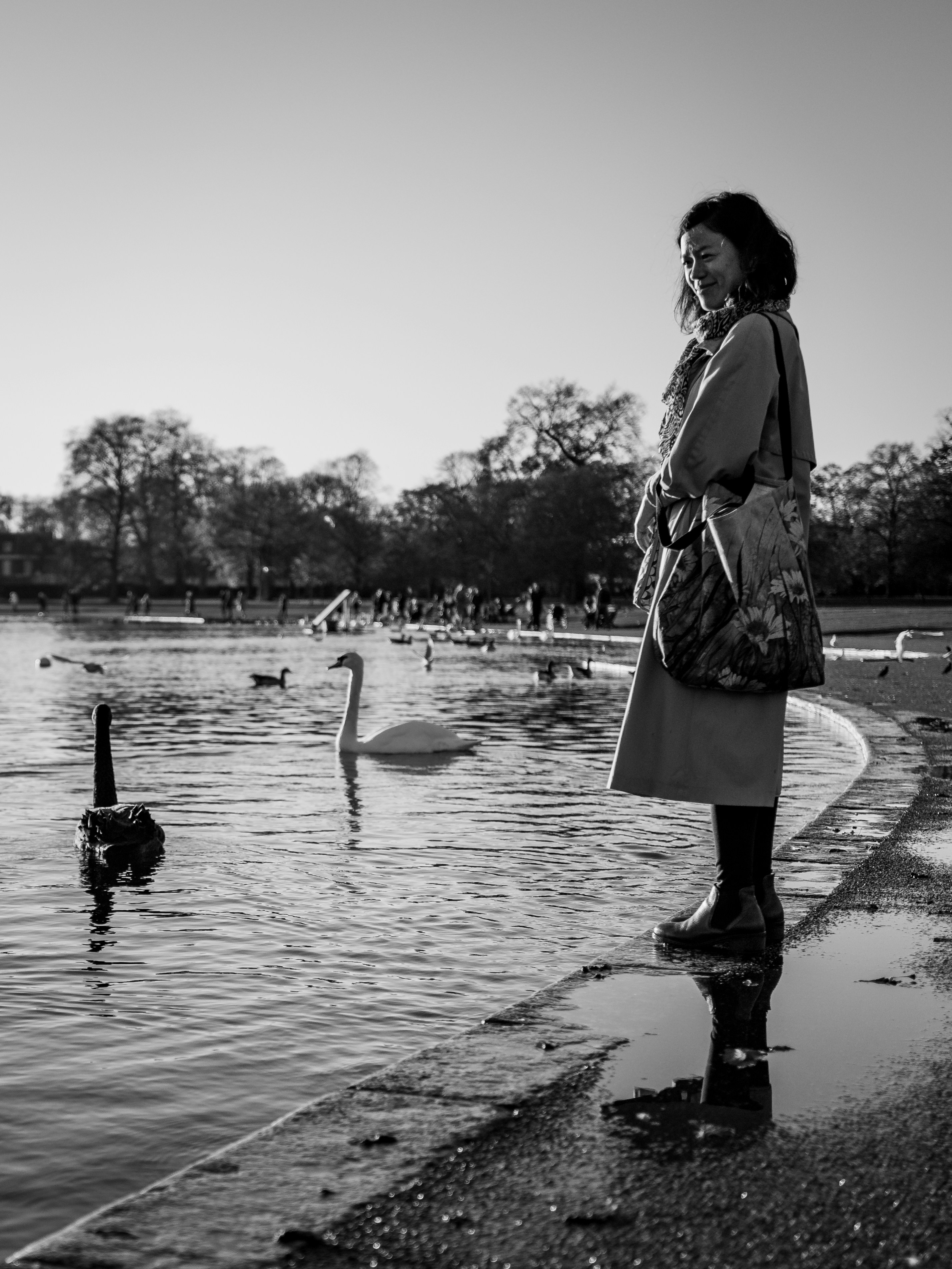 woman in black coat walking on wet road