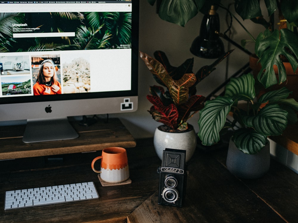 silver imac beside white ceramic mug