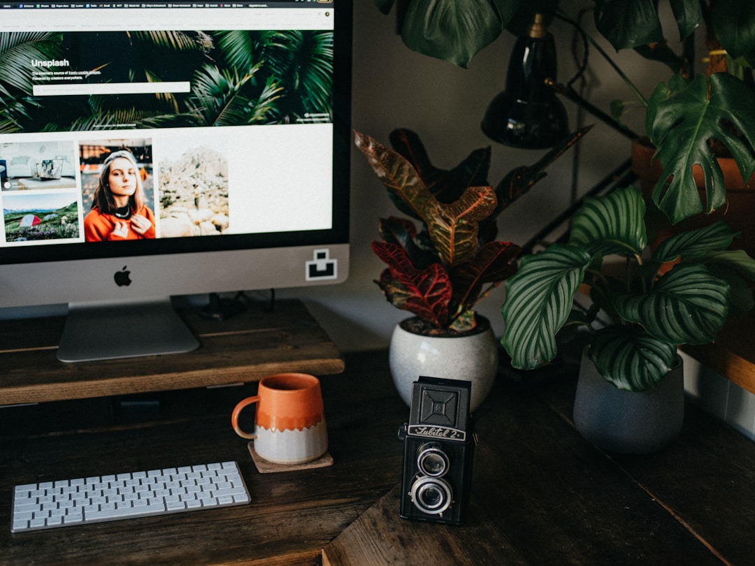 silver imac beside white ceramic mug,