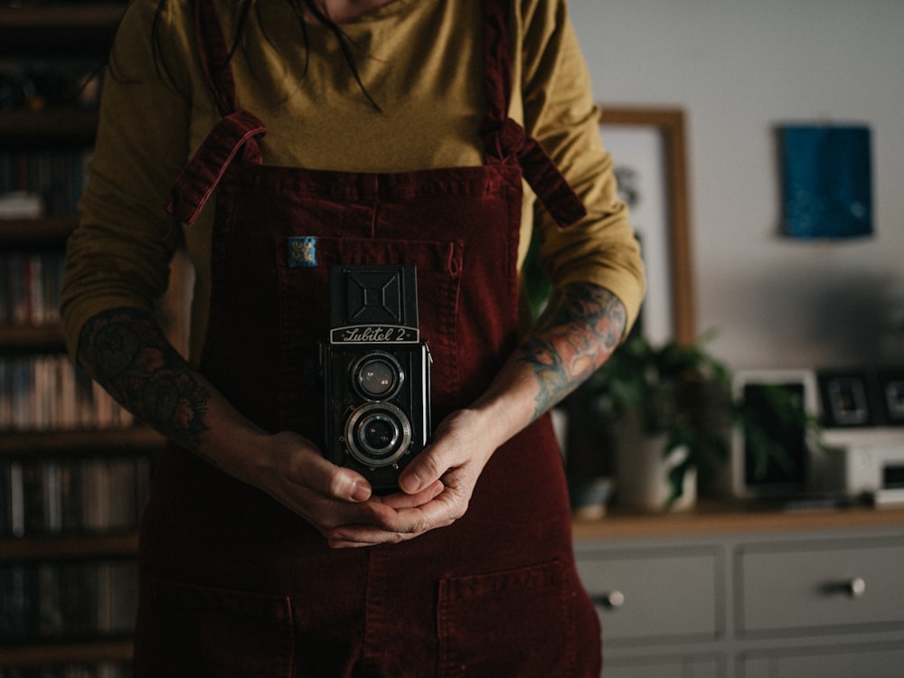 man in brown and black long sleeve shirt holding black and silver camera