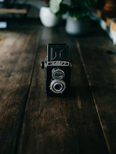 Close-up of a vintage camera resting on a wooden table with soft shadows.
