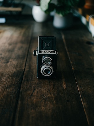 Close-up of a vintage camera on a wooden table, evoking a nostalgic mood.