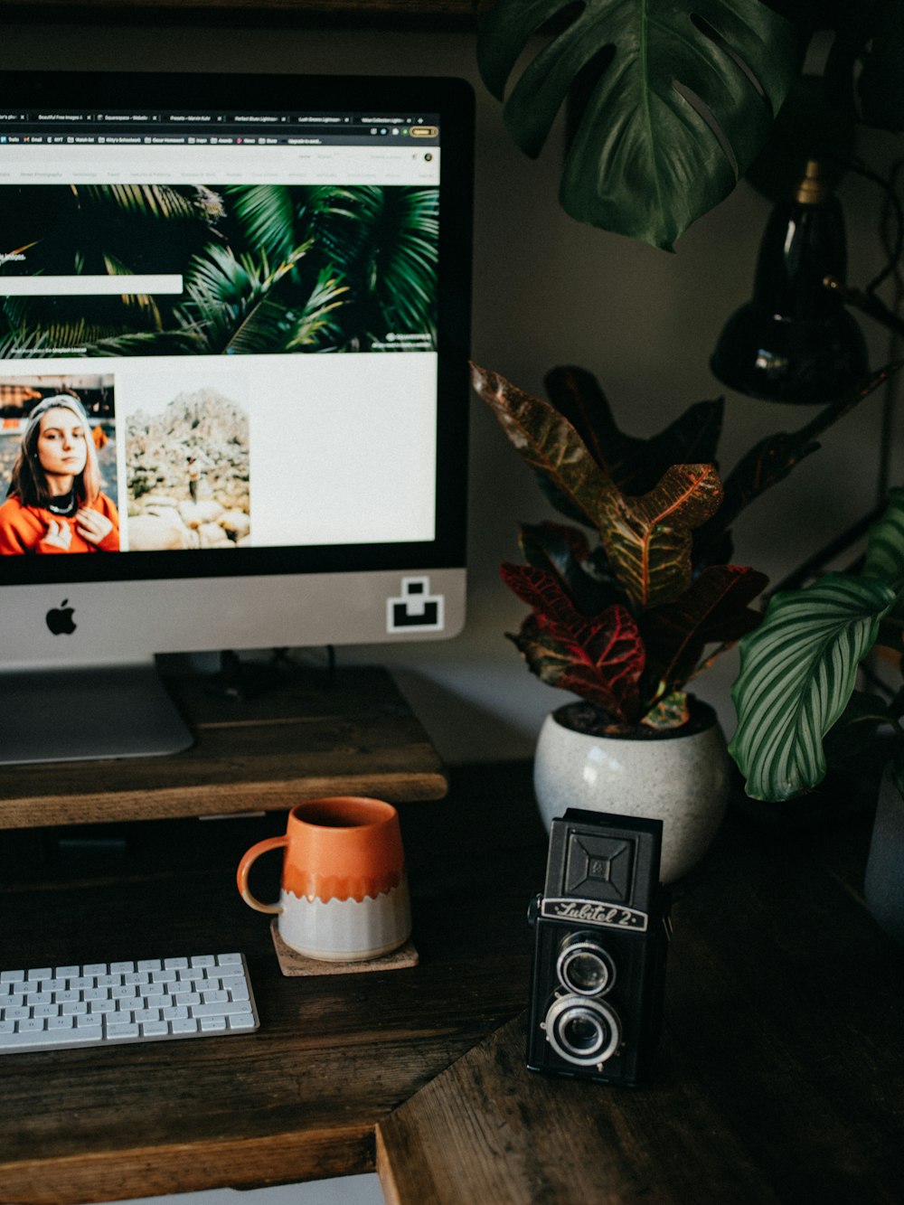 imac prateado com teclado da maçã e caneca de cerâmica branca na mesa de madeira marrom