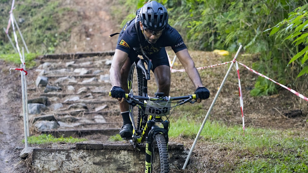 man in black and white shirt riding black mountain bike during daytime