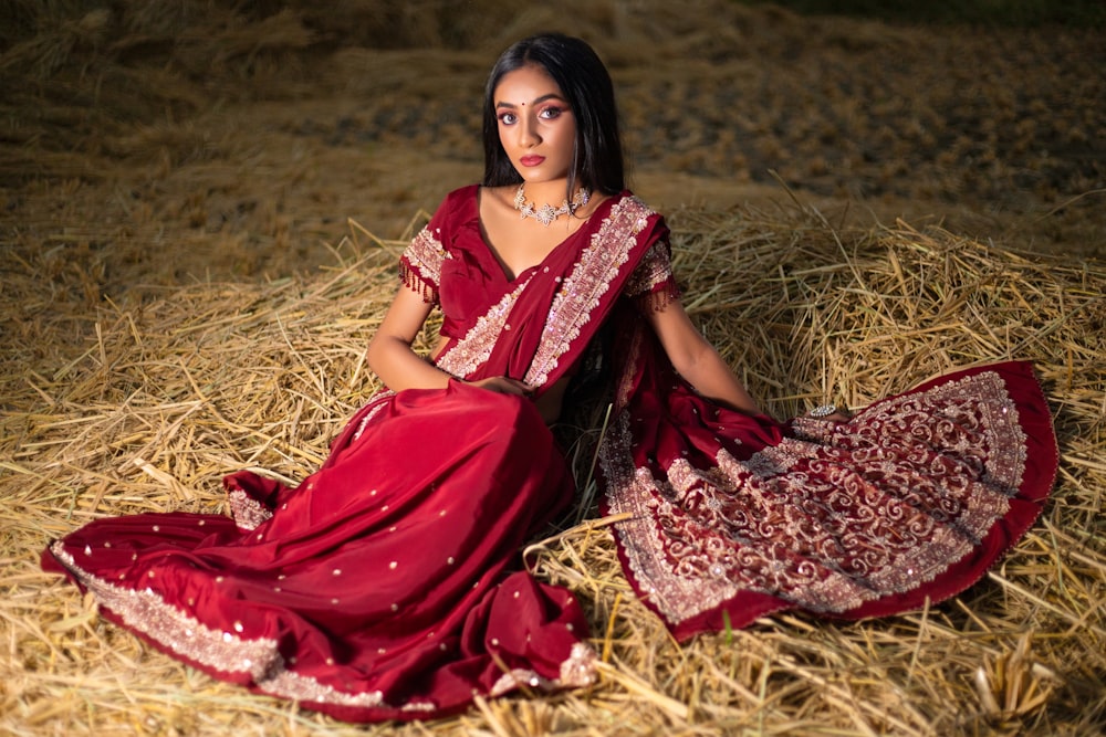 woman in red and white dress sitting on brown grass