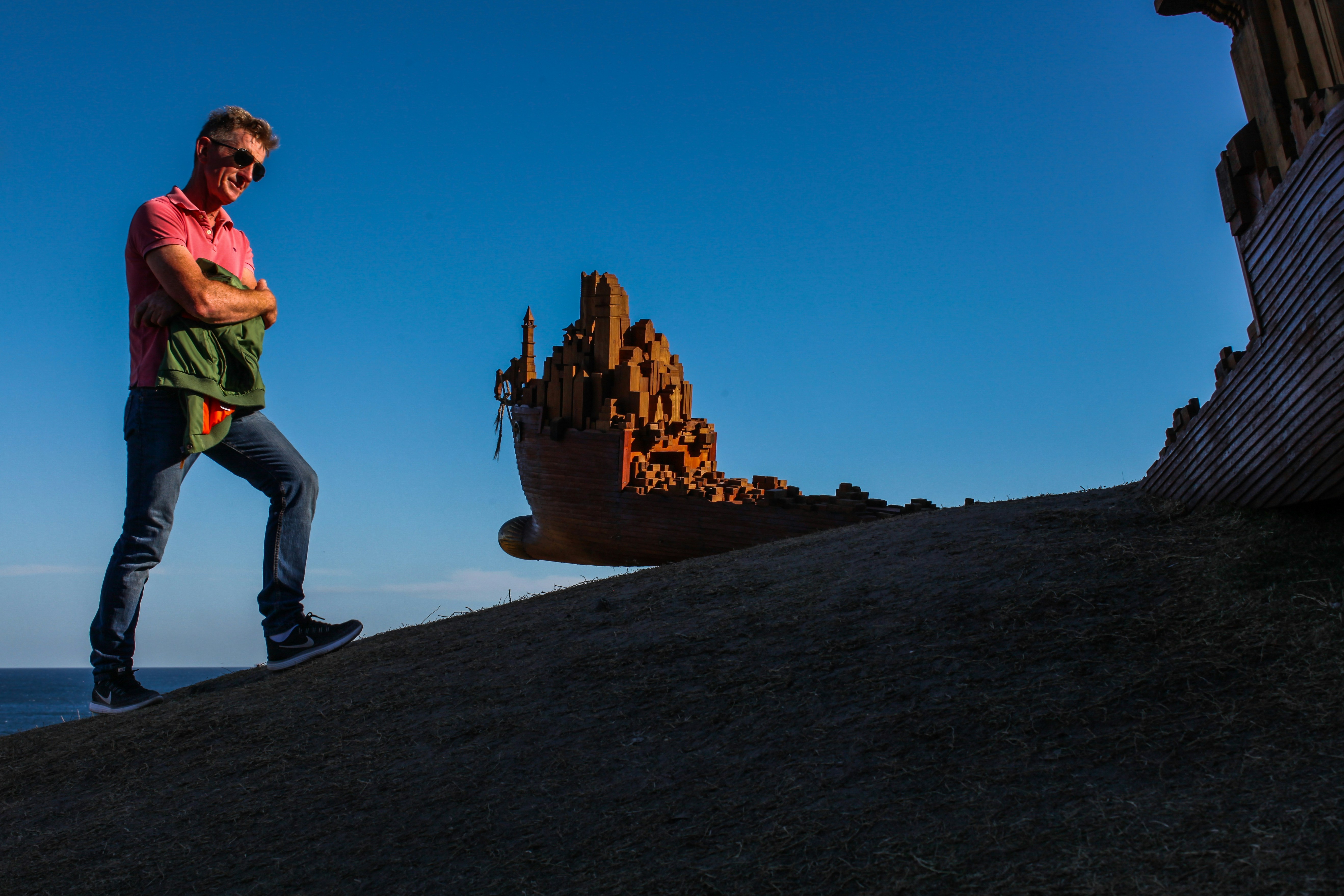 man in green shirt and black pants standing on rock formation during daytime