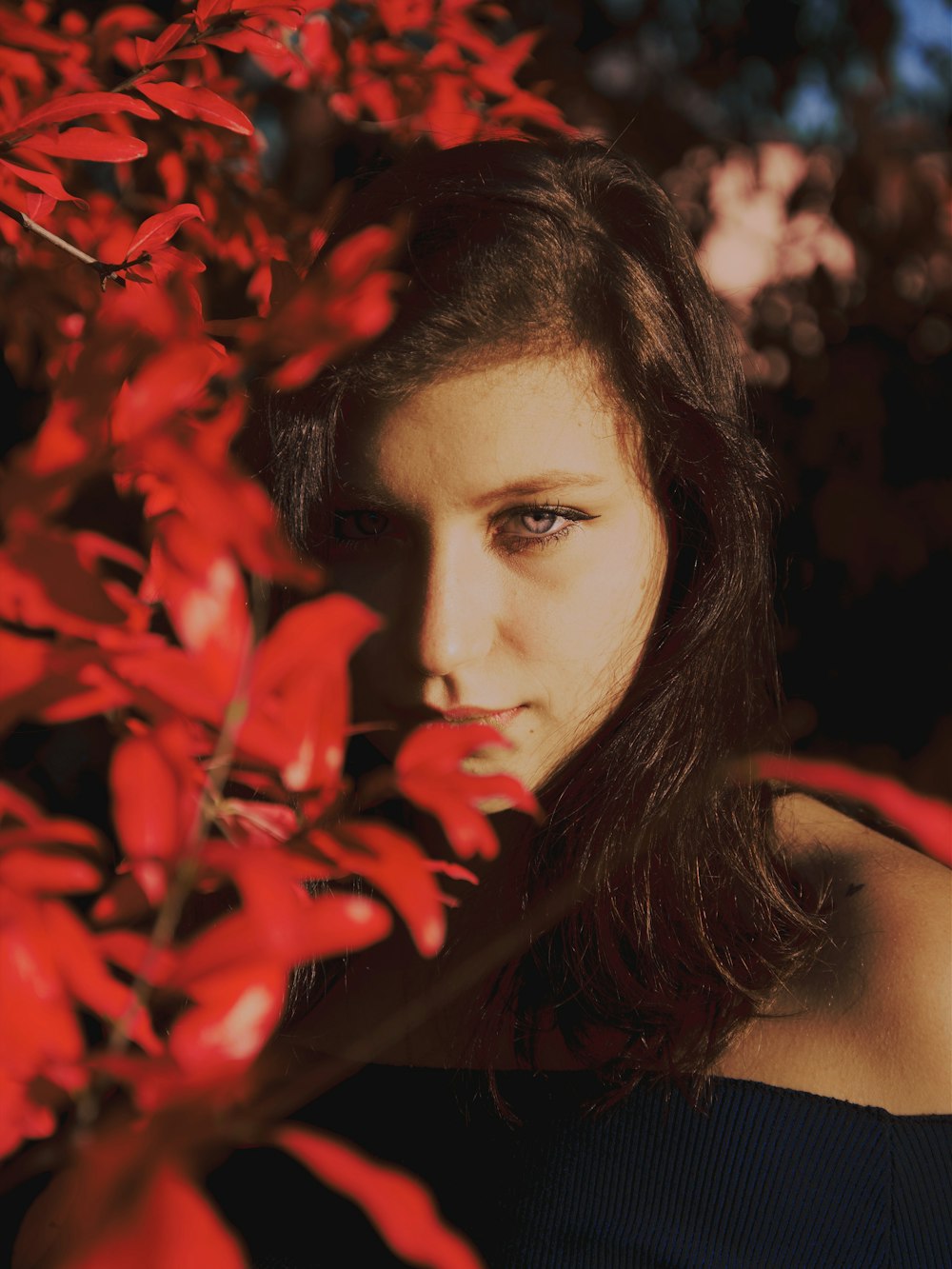 woman in black tank top beside red leaves