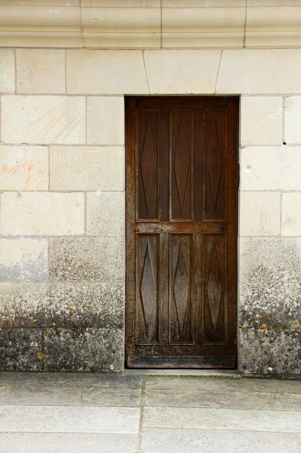 Porta di legno marrone su parete di cemento grigio