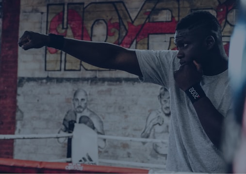 Trainer demonstrating boxing stance and punches to a small group in a gym.