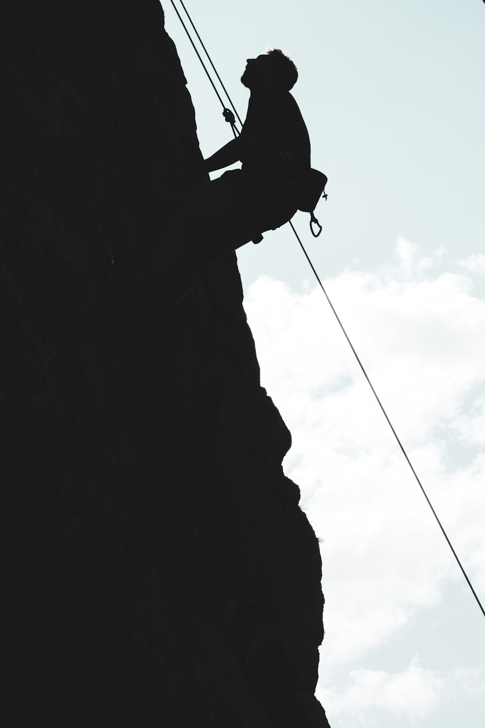 Silhouette eines Mannes, der tagsüber auf den Berg klettert