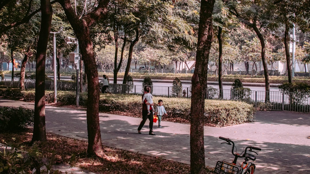 2 women walking on sidewalk near trees during daytime