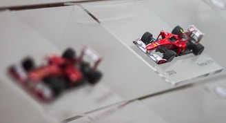 A sleek red Ferrari F1 car model displayed on a shelf.