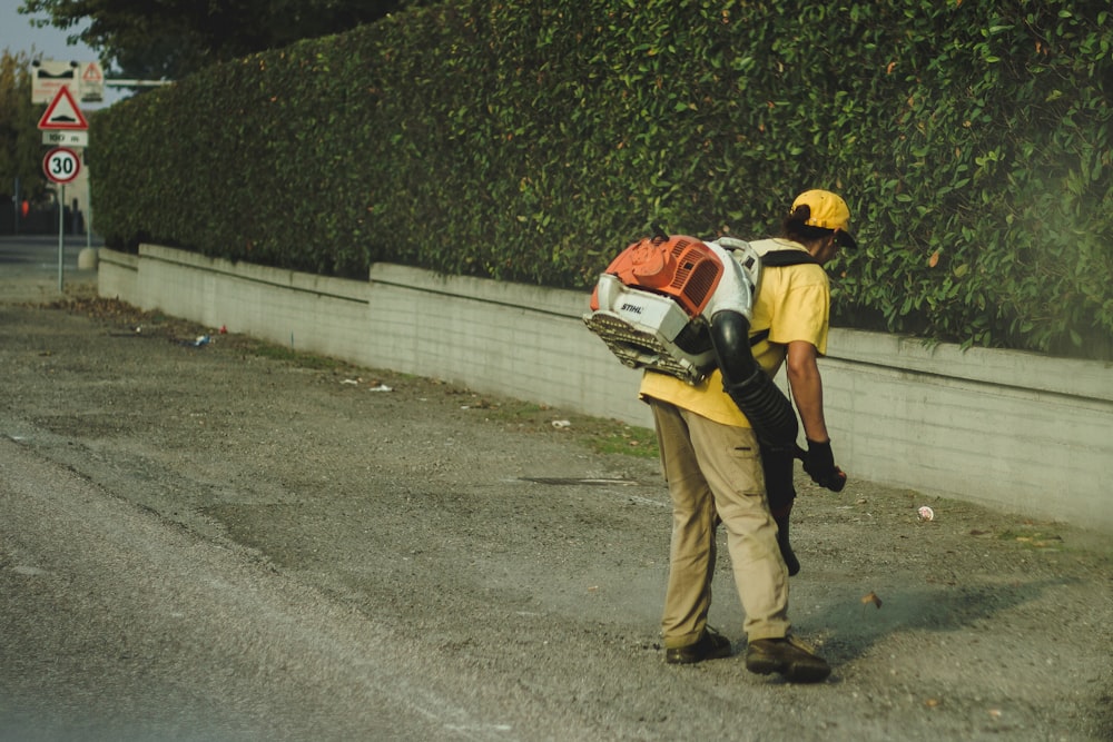 2 men in orange and black jacket walking on gray asphalt road during daytime