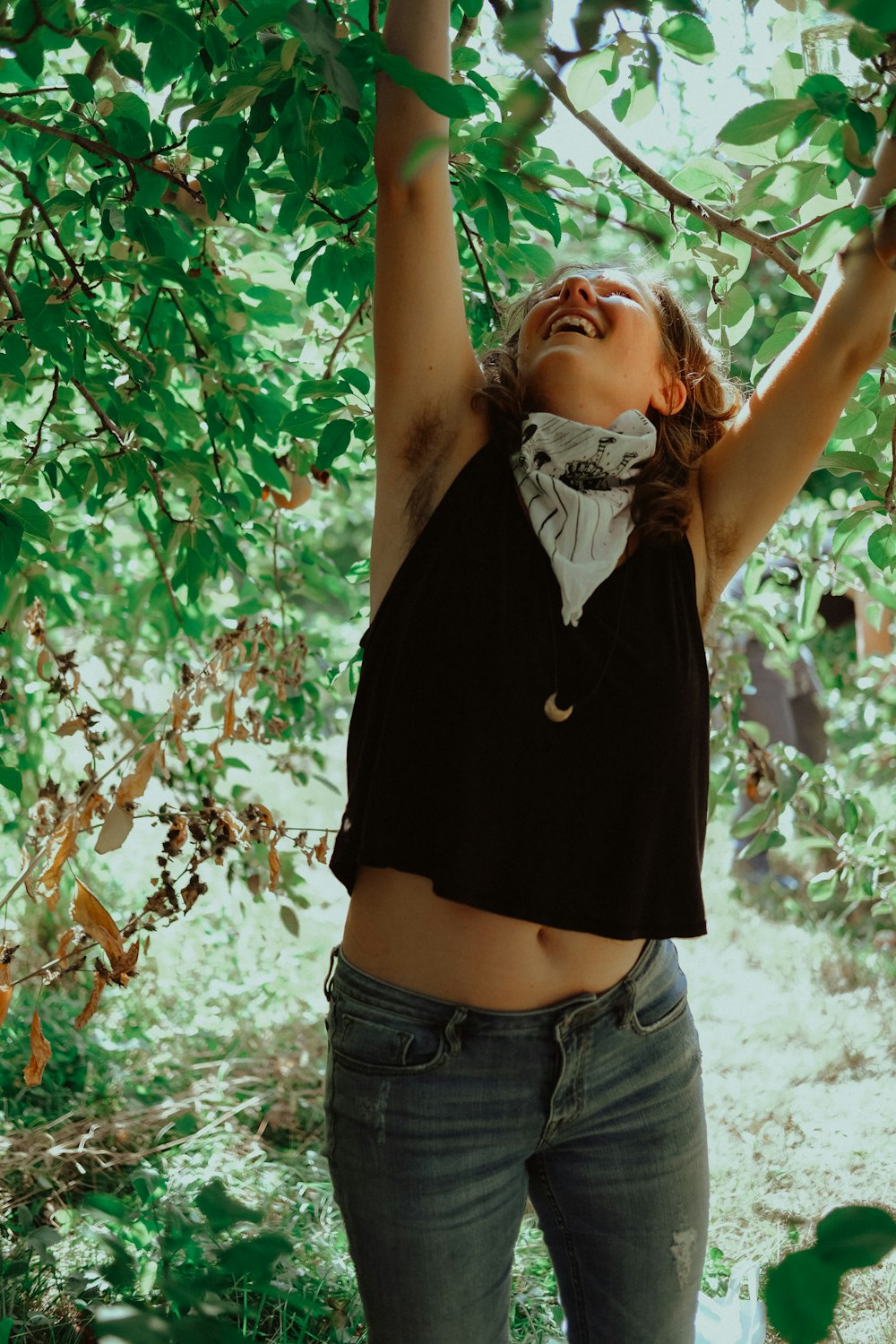 woman in black shirt and blue denim shorts standing under green tree during daytime