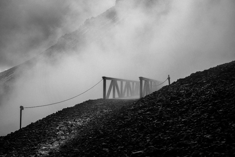 grayscale photo of bridge under cloudy sky