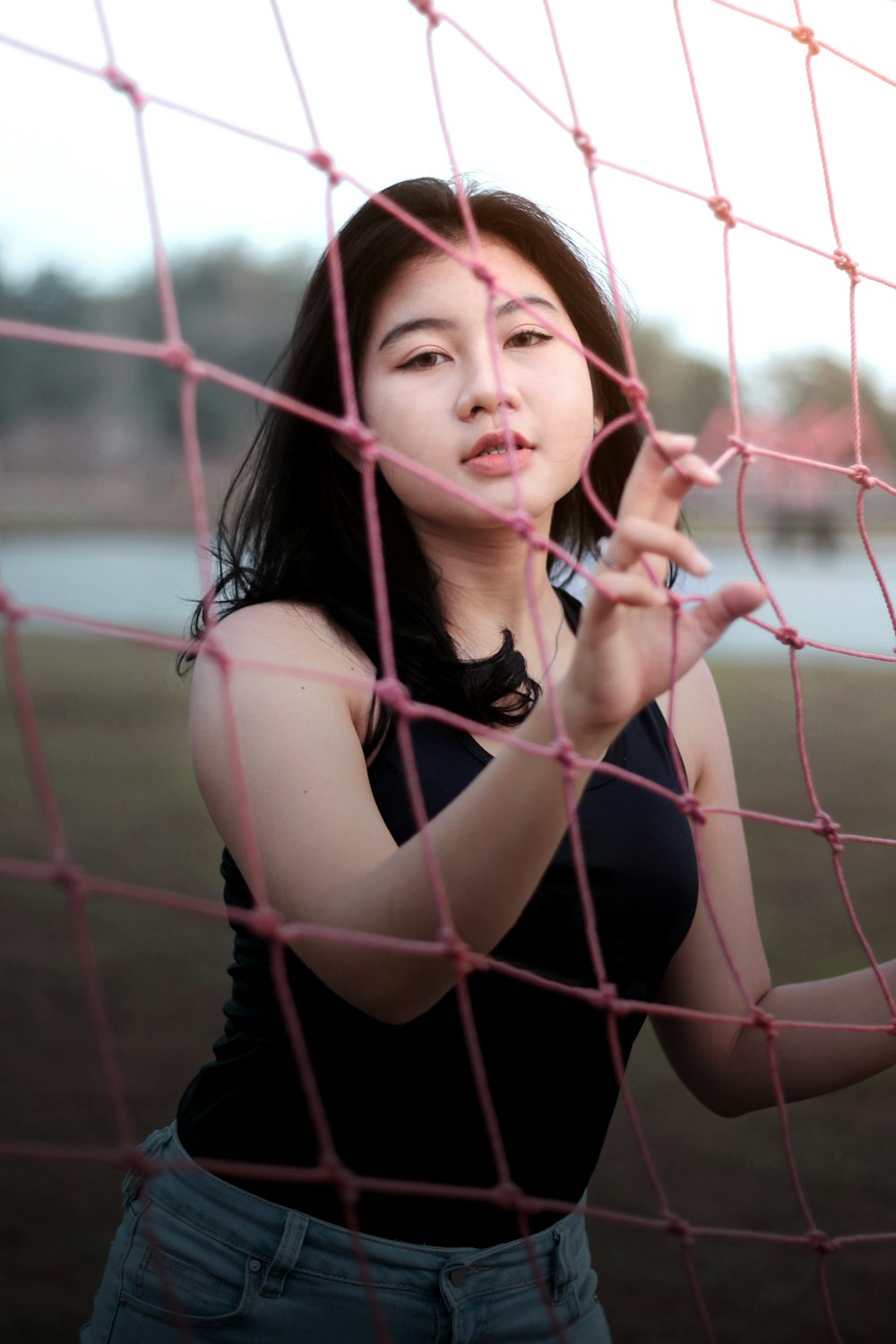 woman in black tank top leaning on chain link fence