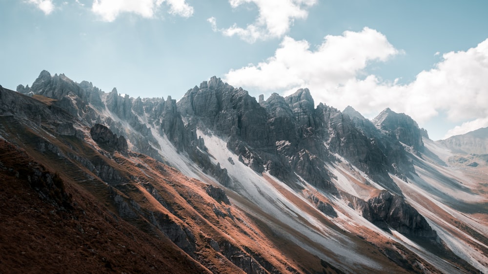 brown and gray mountains under white clouds and blue sky during daytime