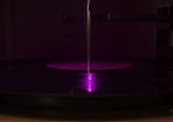 Close-up of vinyl records spinning on a turntable with purple ambient lighting.
