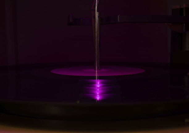 Moody black-and-white shot of Apollo at the turntable, vinyl records stacked nearby.