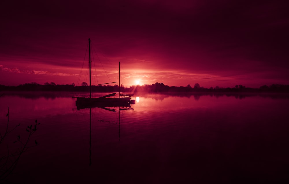 silhouette de bateau sur la mer pendant le coucher du soleil