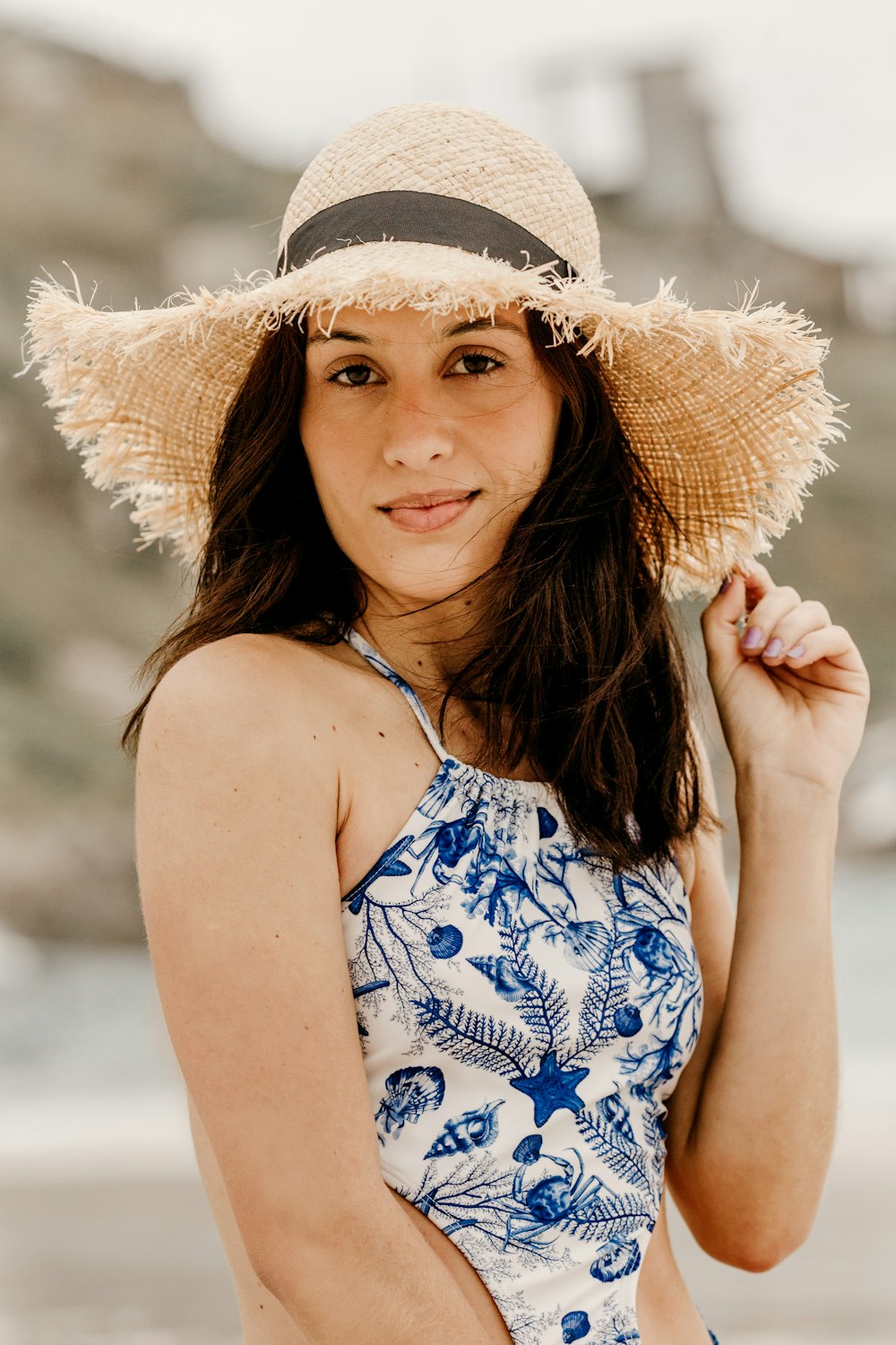 Femme en débardeur floral bleu et blanc portant un chapeau de soleil marron
