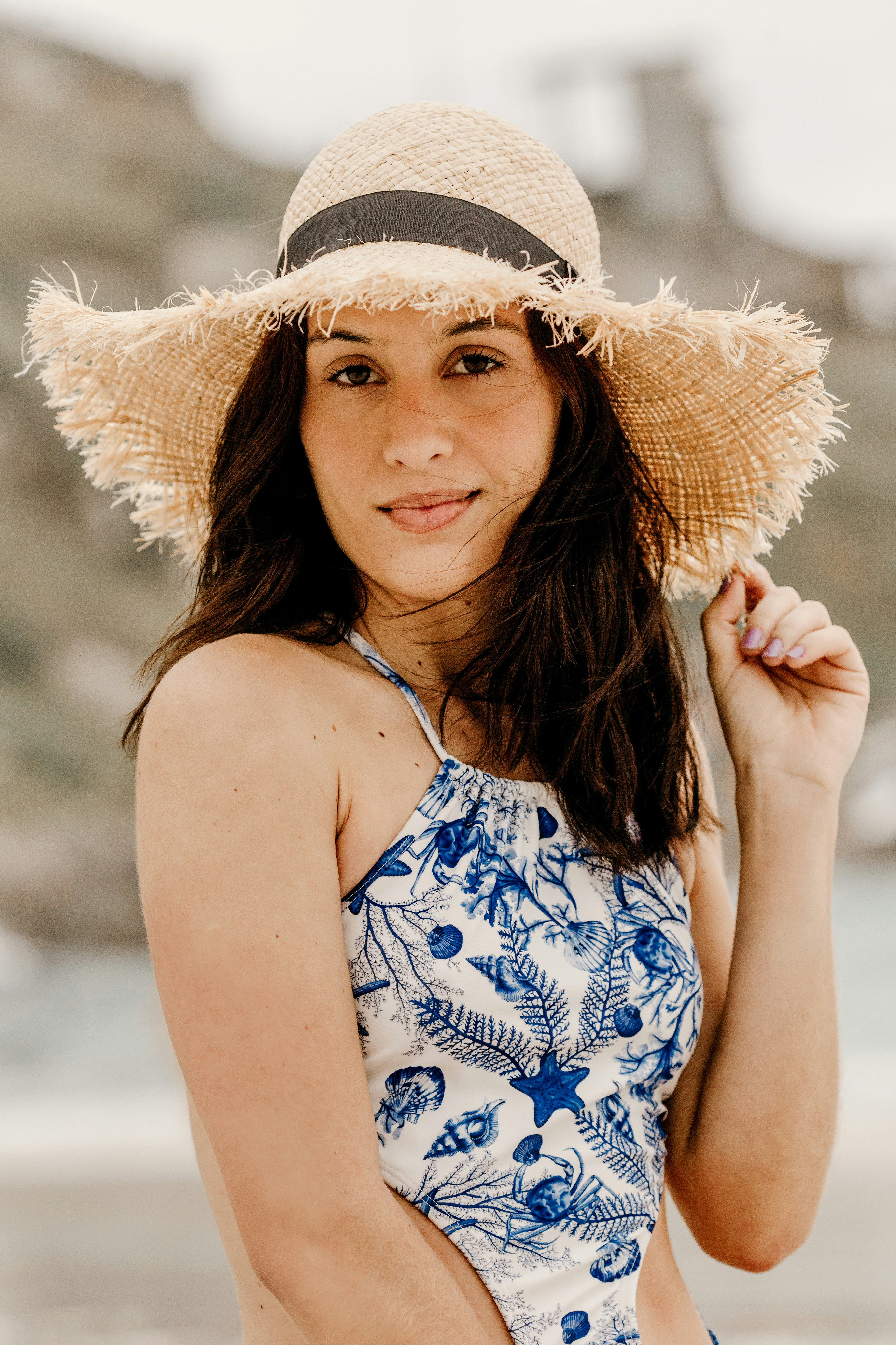 woman in blue and white floral tank top wearing brown sun hat