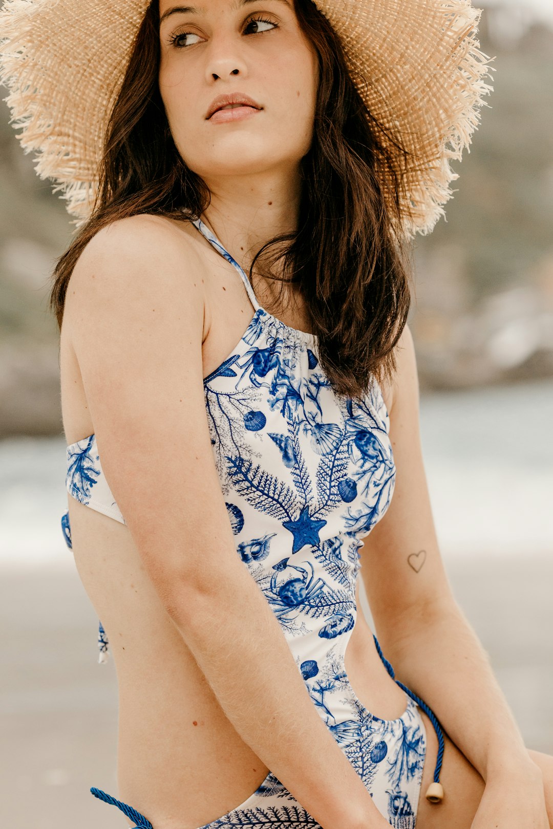 woman in blue and white floral spaghetti strap top wearing brown sun hat