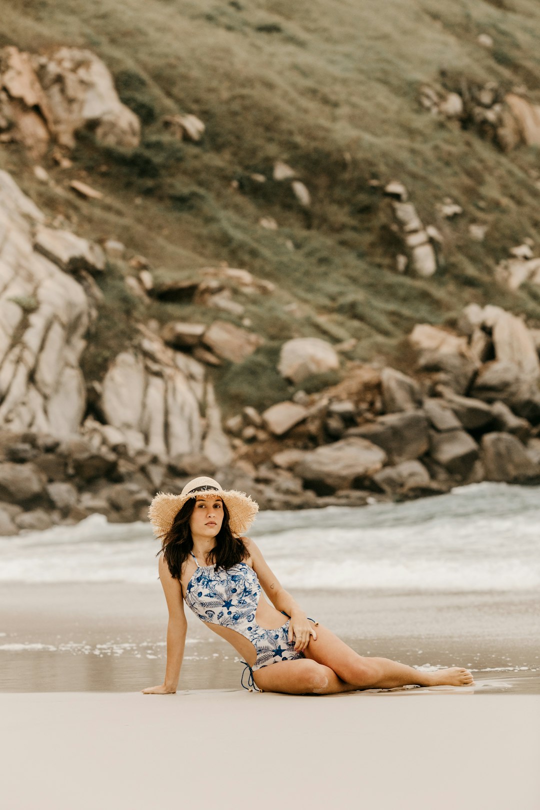 woman in white and blue floral dress sitting on beach shore during daytime