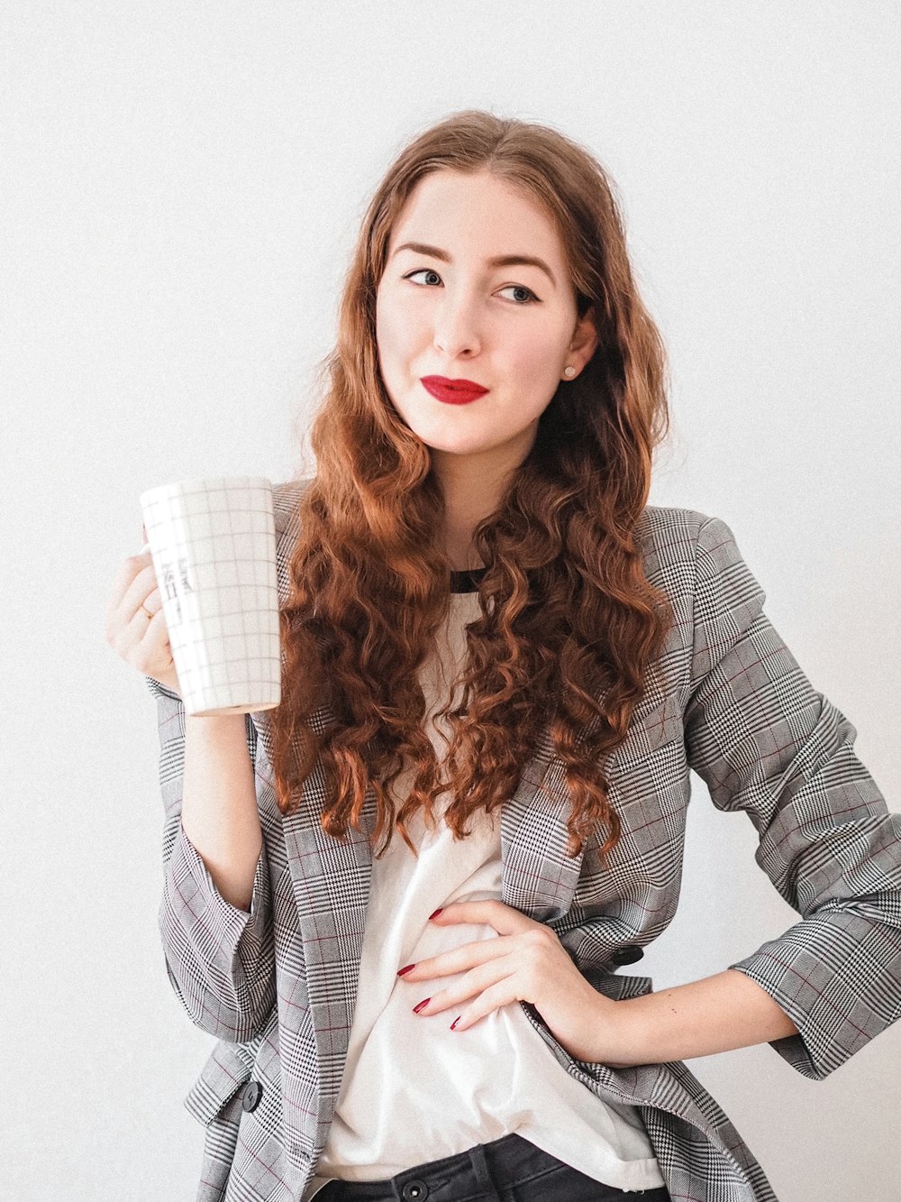 Femme en cardigan gris tenant une tasse en céramique blanche