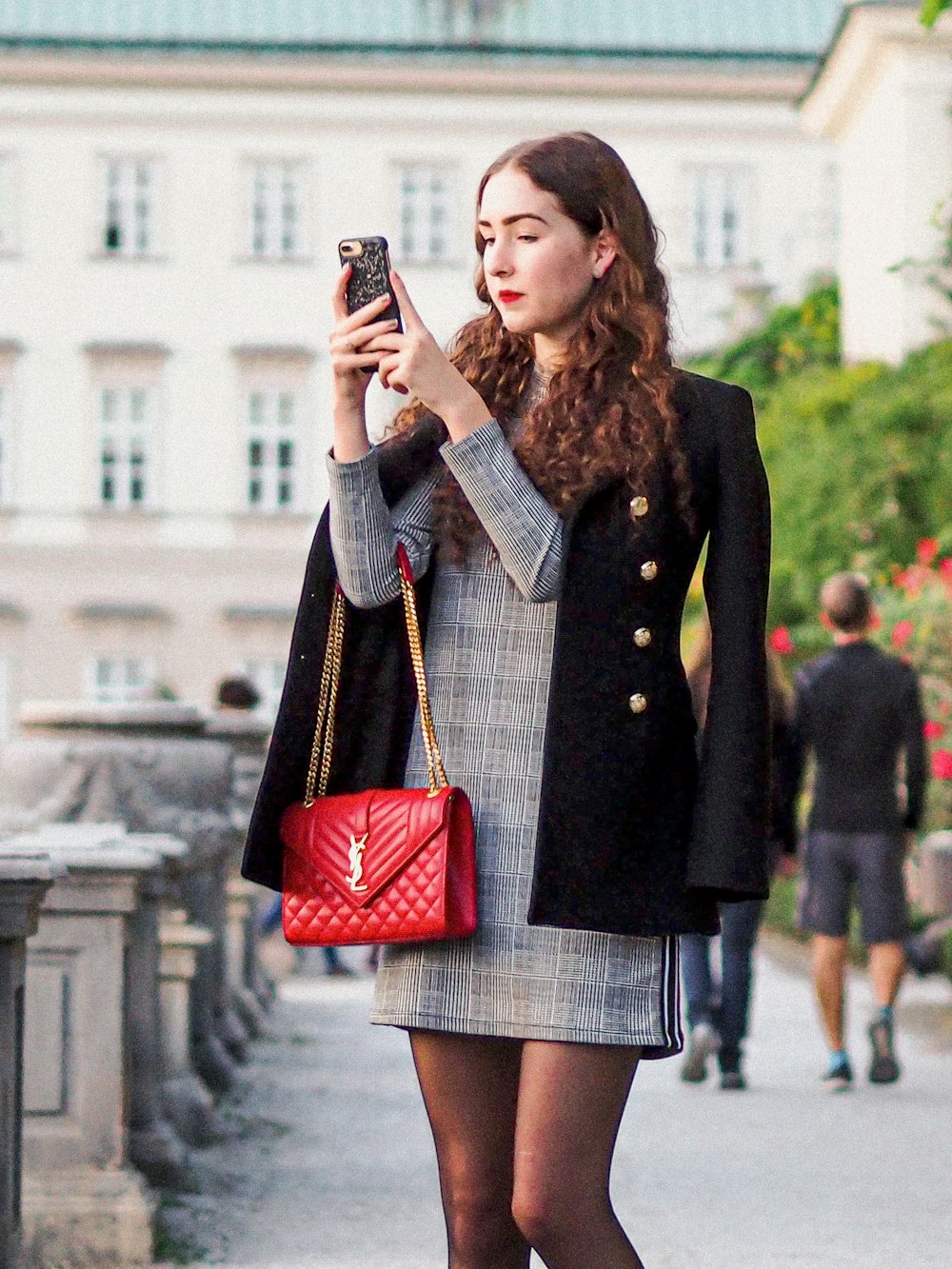 woman in black coat holding red leather handbag