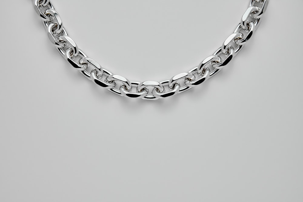 silver chain link bracelet on white surface