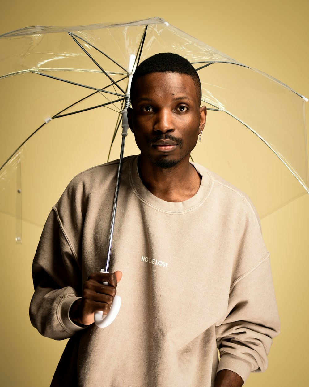 man in white sweater holding umbrella