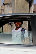 A young learner driver receiving friendly guidance from a patient instructor in a car.