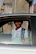 A young teen receiving driving instructions from a cheerful instructor beside a car.