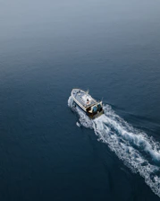 Sport fishing boat cutting through calm blue waters at sunrise.
