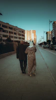A cinematic capture of a couple walking hand-in-hand along a charcoal-toned urban street at golden hour.