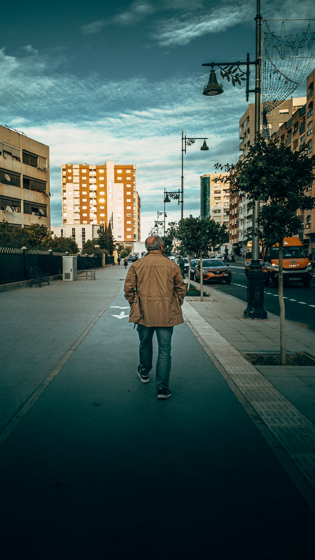 man in brown jacket standing on sidewalk during daytime