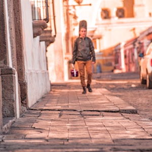 man in black jacket walking on sidewalk during daytime