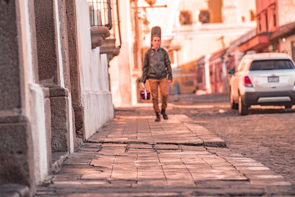 man in black jacket walking on sidewalk during daytime