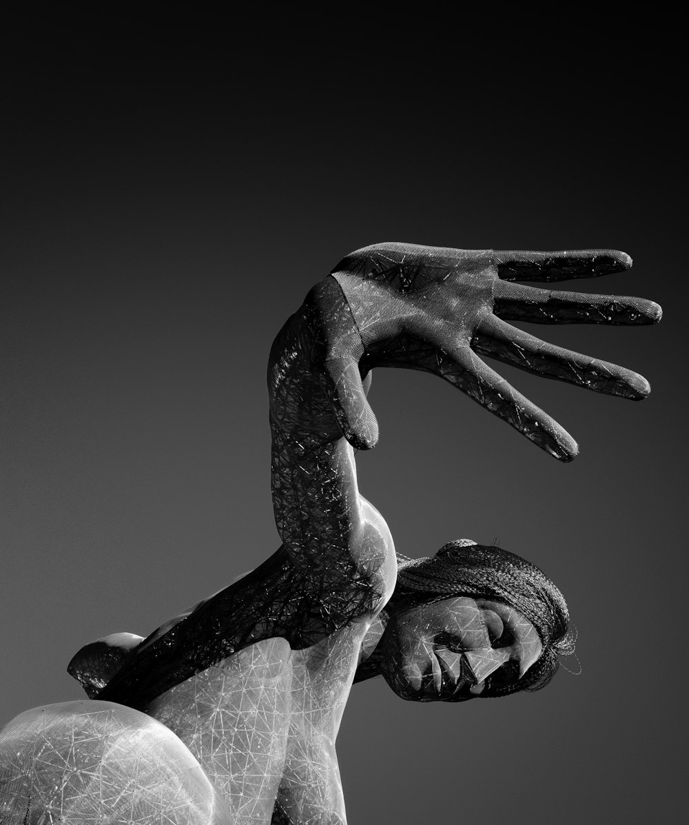 foto em tons de cinza do homem que segura a estátua da mão das mulheres