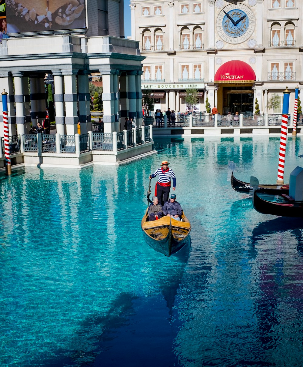 man in black and orange jacket riding on brown boat on water during daytime