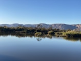 A calm lake reflecting the surrounding mountains and sky.