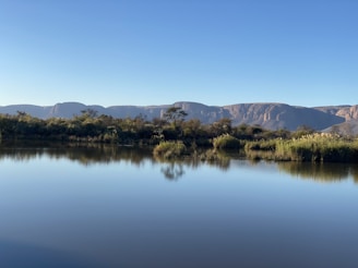 A calm lake reflecting surrounding mountains under a clear sky.