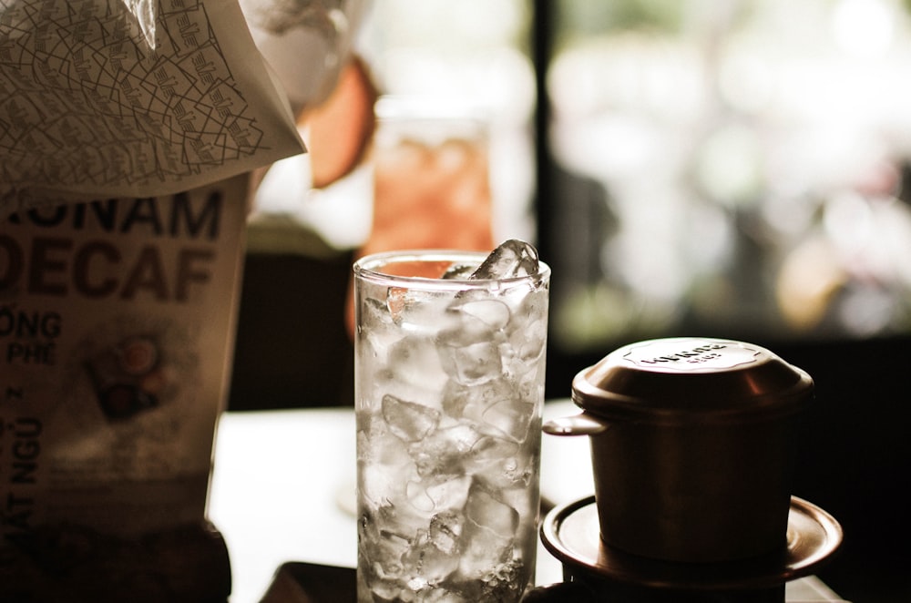 clear drinking glass beside black ceramic mug