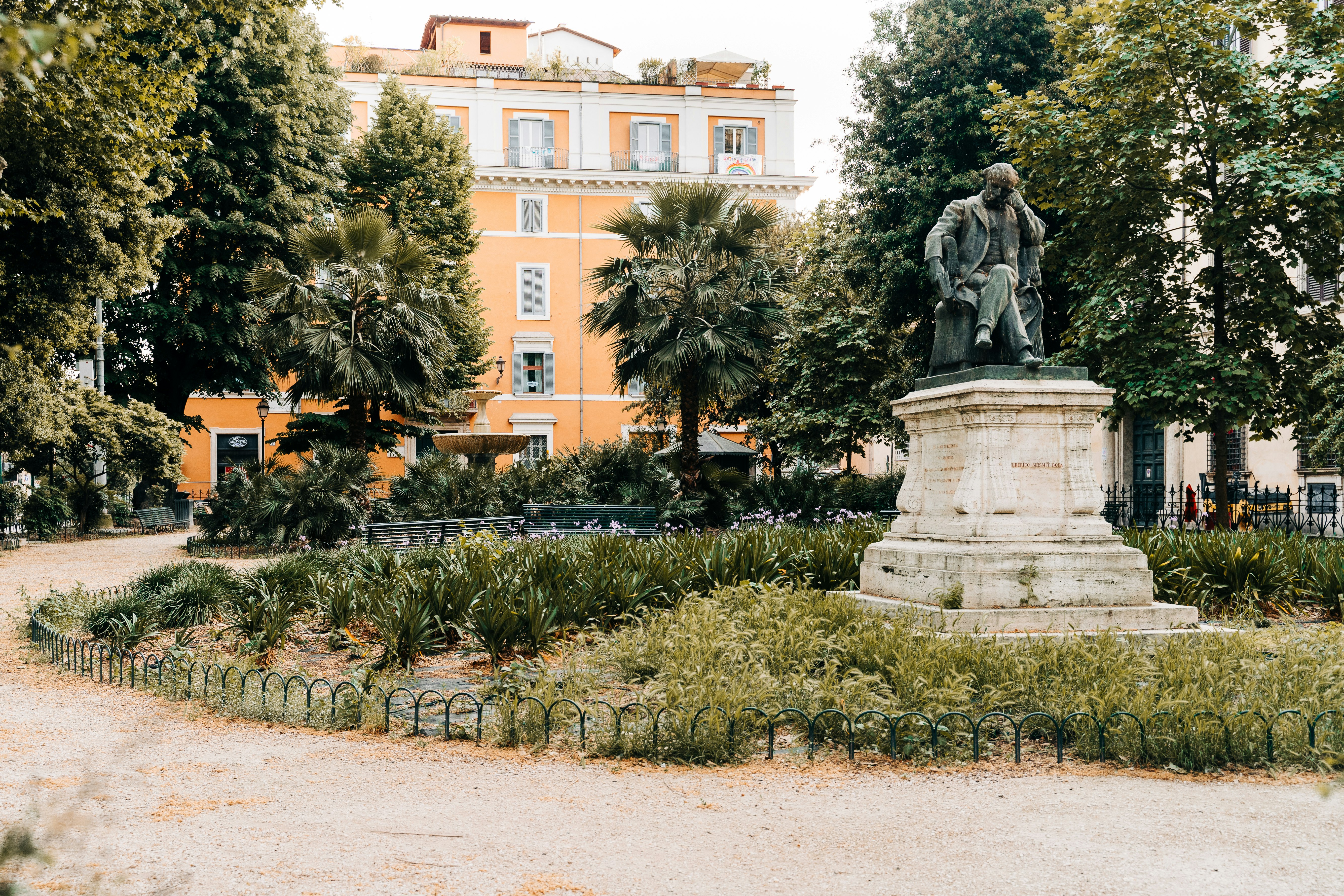 statue of man riding horse near green trees and brown building during daytime