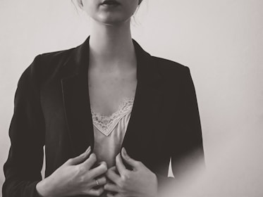 A minimalist outfit featuring a sleek, structured blazer over a delicate silk top, captured in natural daylight.