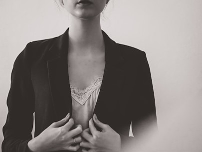A softly lit photo of a model wearing a flowing blouse and tailored trousers in muted tones.