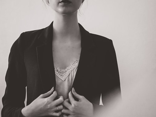 A close-up shot of a model wearing a sharp, tailored navy blazer with subtle texture under soft natural light.