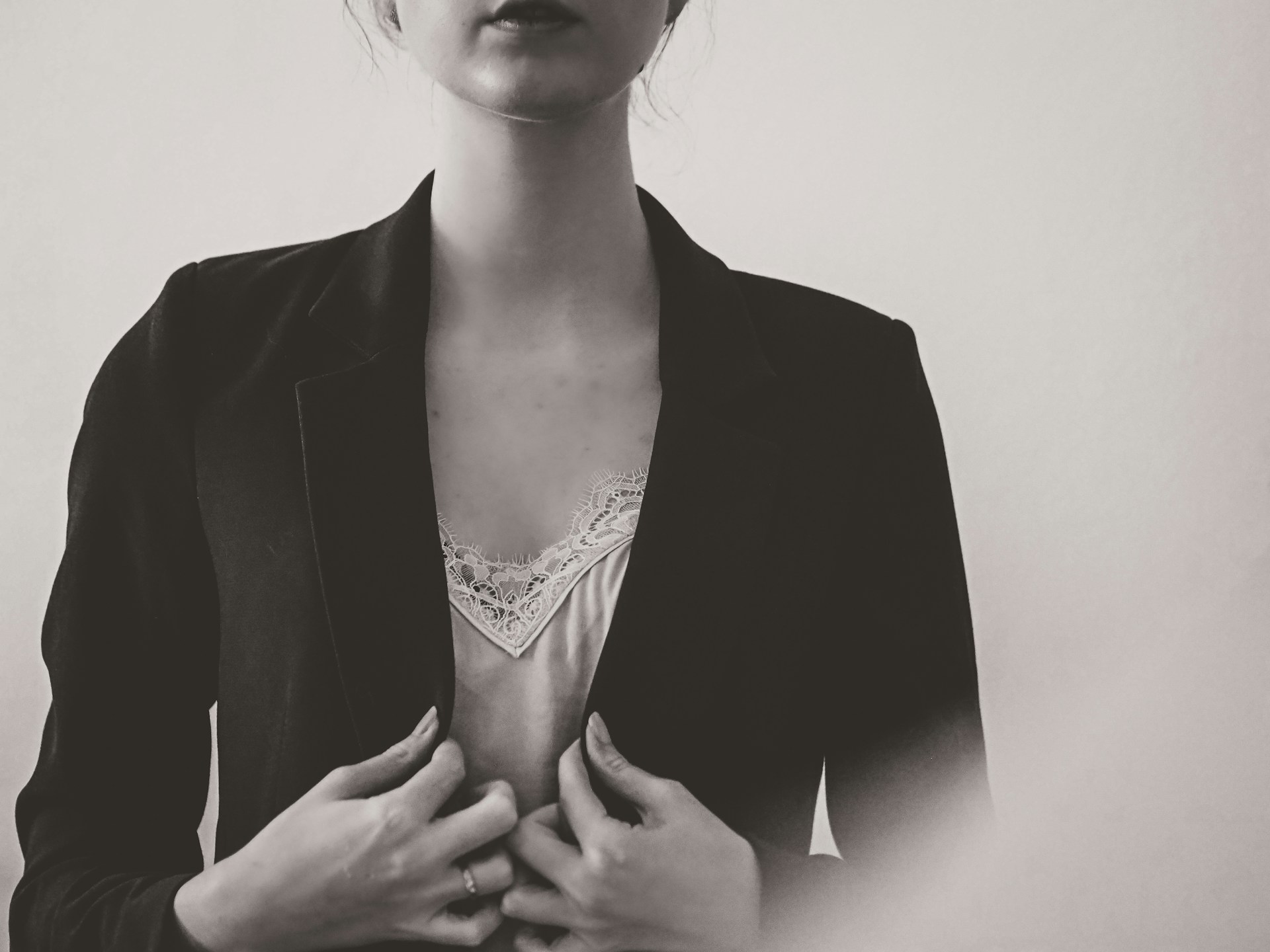 A softly lit photo of a model wearing a sleek, neutral-toned blazer paired with tailored trousers, standing against a minimalist backdrop.