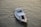 A small white motorboat is navigating through calm waters. The boat has a covered cabin with windows, life buoys attached to the sides, and a small antenna on top. The water reflects a golden hue under the sunlight.